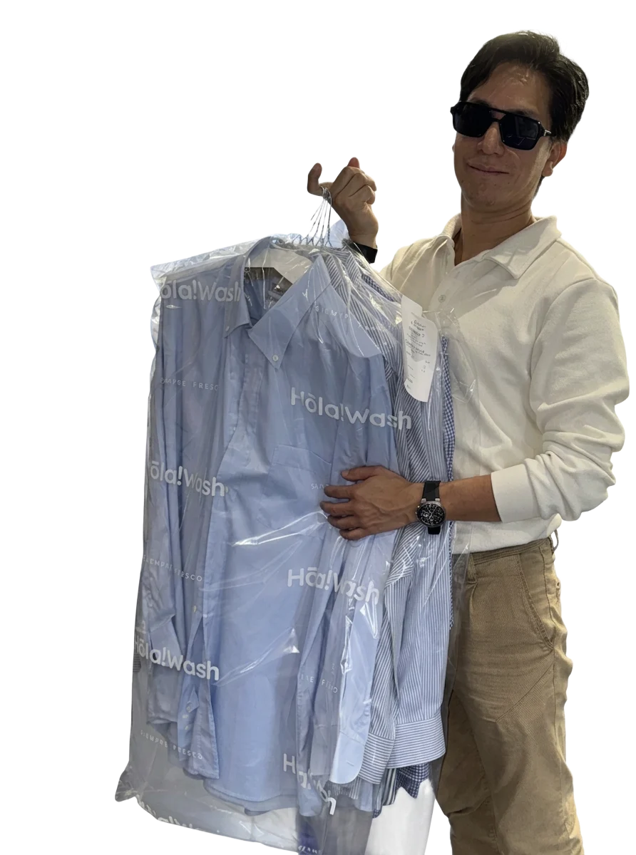 HolaWash team member with freshly pressed shirts in protective covers
